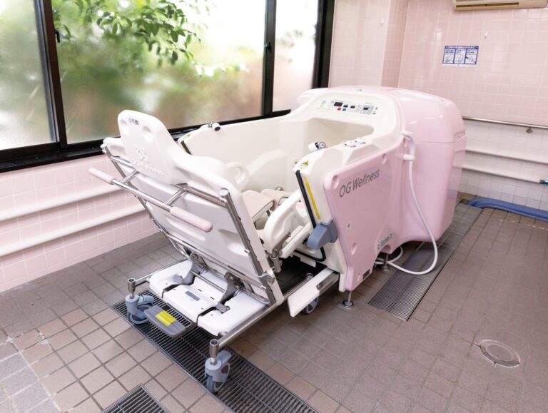 介護用入浴機器を備えた浴室。ピンク色の機械式入浴装置が設置されている。