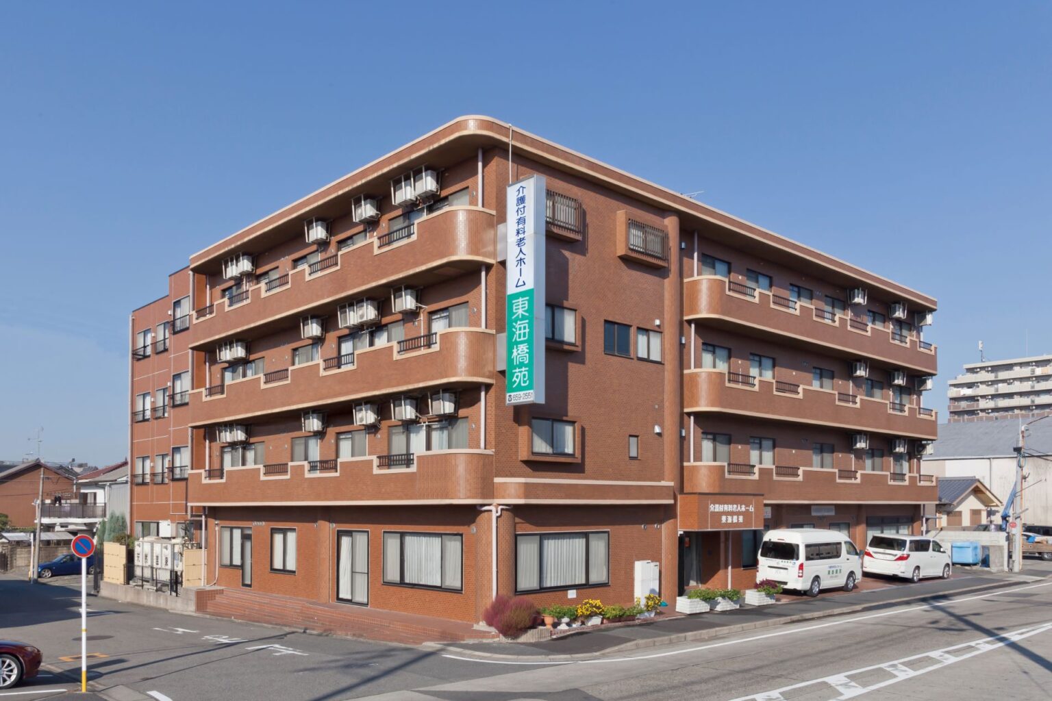 赤茶色レンガ造りの介護施設の建物外観。晴天下で全体が見える。